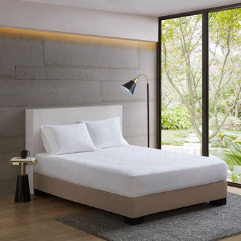 Quilted mattress pad displayed on a bed with clean, minimal bedding